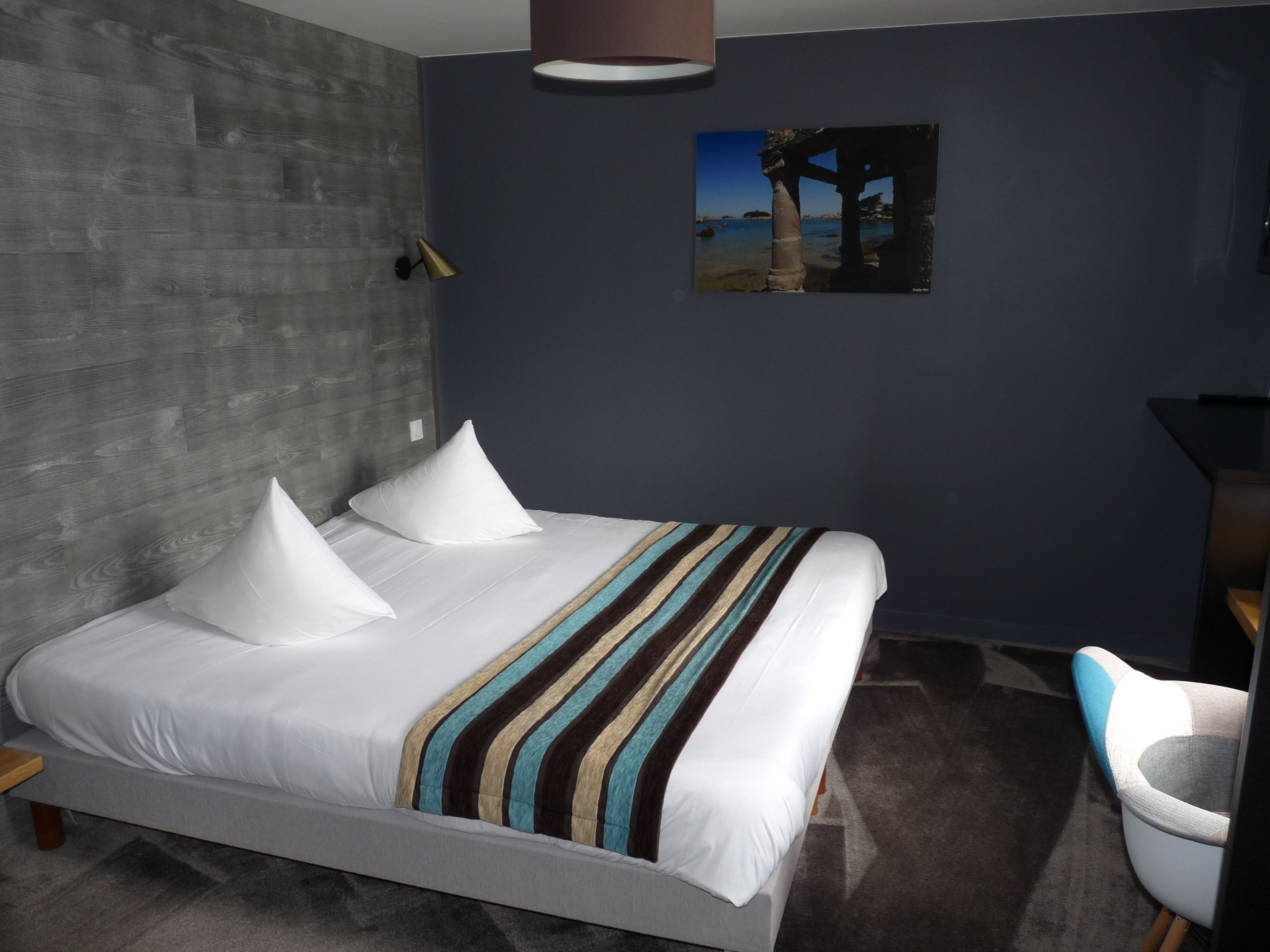 Una camera d'albergo moderna con un letto grande, una scrivania e una sedia.