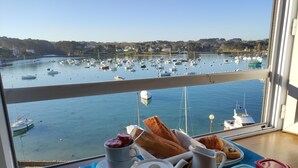A breakfast tray with toast, jam, coffee, and juice on a balcony overlooking a marina with boats. - Hôtel des Rochers (Perros-Guirec)