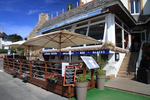 Enjoy dining al fresco at Des Rochers, where lush greenery surrounds the outdoor seating area.