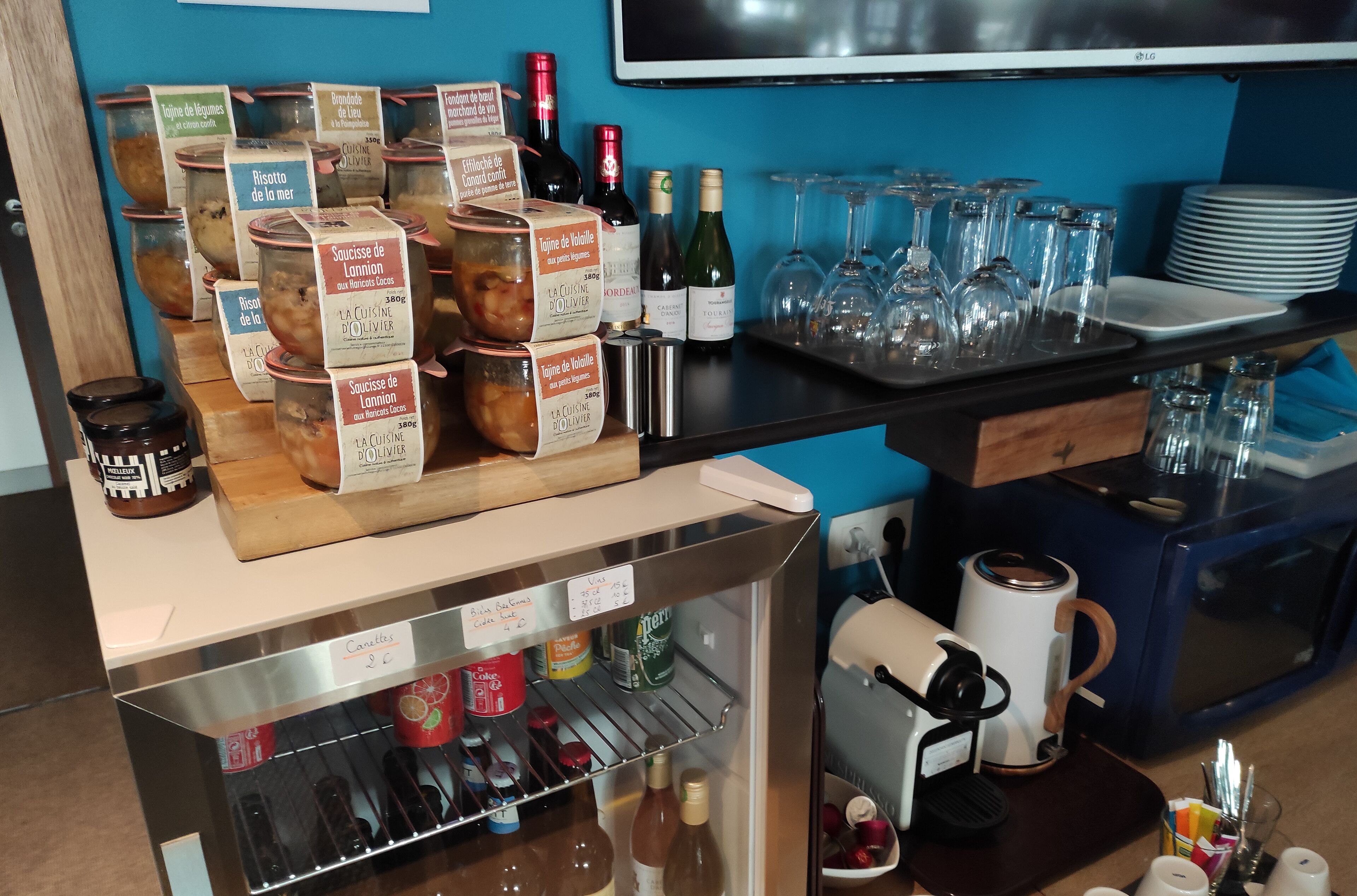 A bar area with jars of preserves, wine bottles, glasses, and a coffee machine.