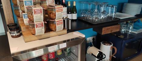 A bar area with jars of preserves, wine bottles, glasses, and a coffee machine.