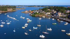 A coastal town with numerous boats docked along the harbor, surrounded by residential buildings and greenery. - Hôtel des Rochers (Perros-Guirec)