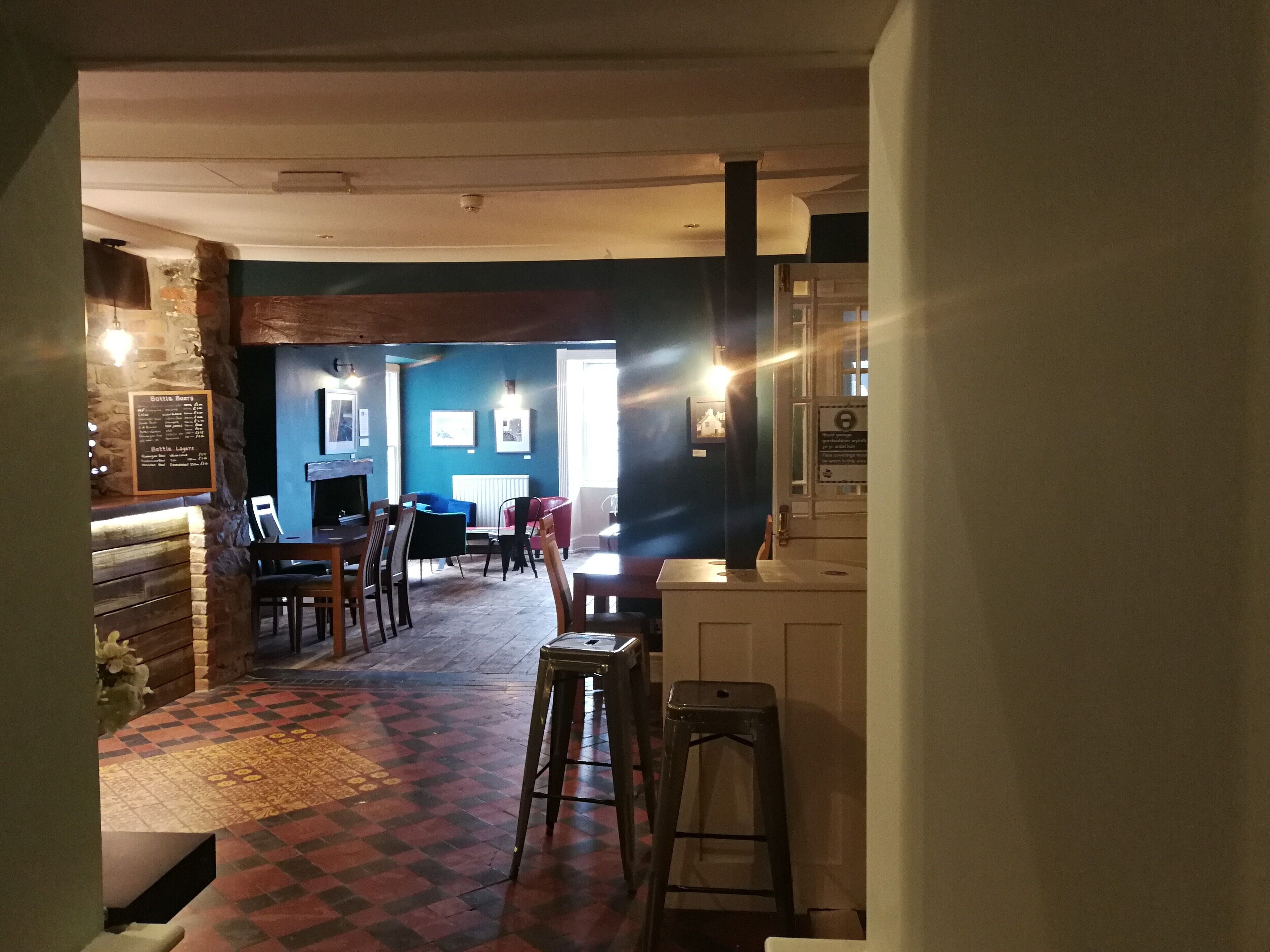 A restaurant interior with a checkered floor, wooden furniture, and a menu board.