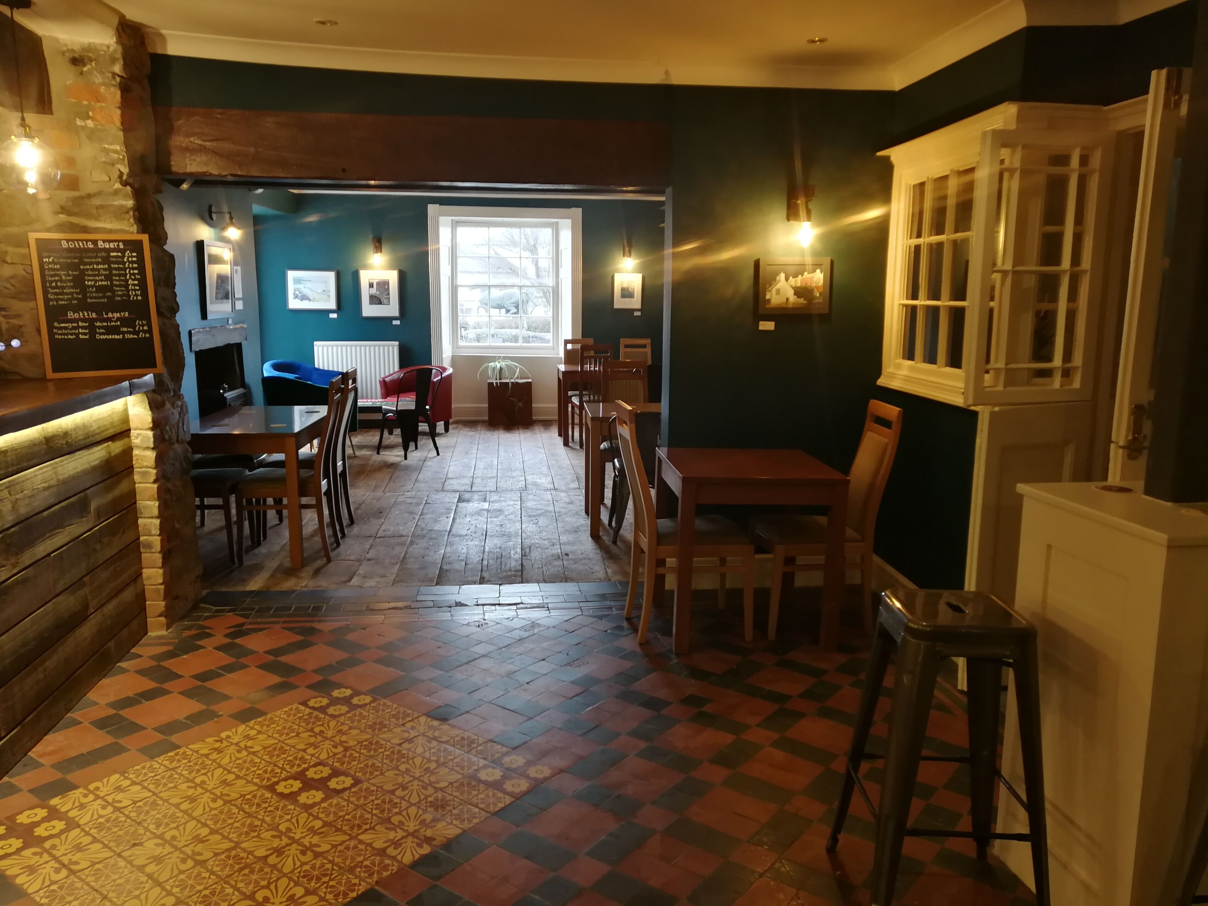 A cozy restaurant with a checkered floor, wooden furniture, and a menu board on the left.