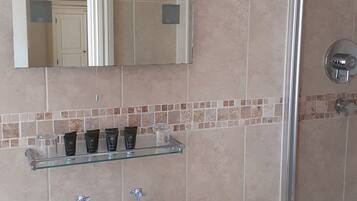 A bathroom with a white sink, two faucets, a mirror, and a shower area.