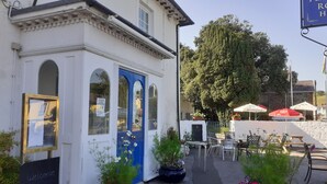 A building with a blue door, outdoor seating, and potted plants. - Feathers Hotel, Bar and Restaurant (Aberaeron)