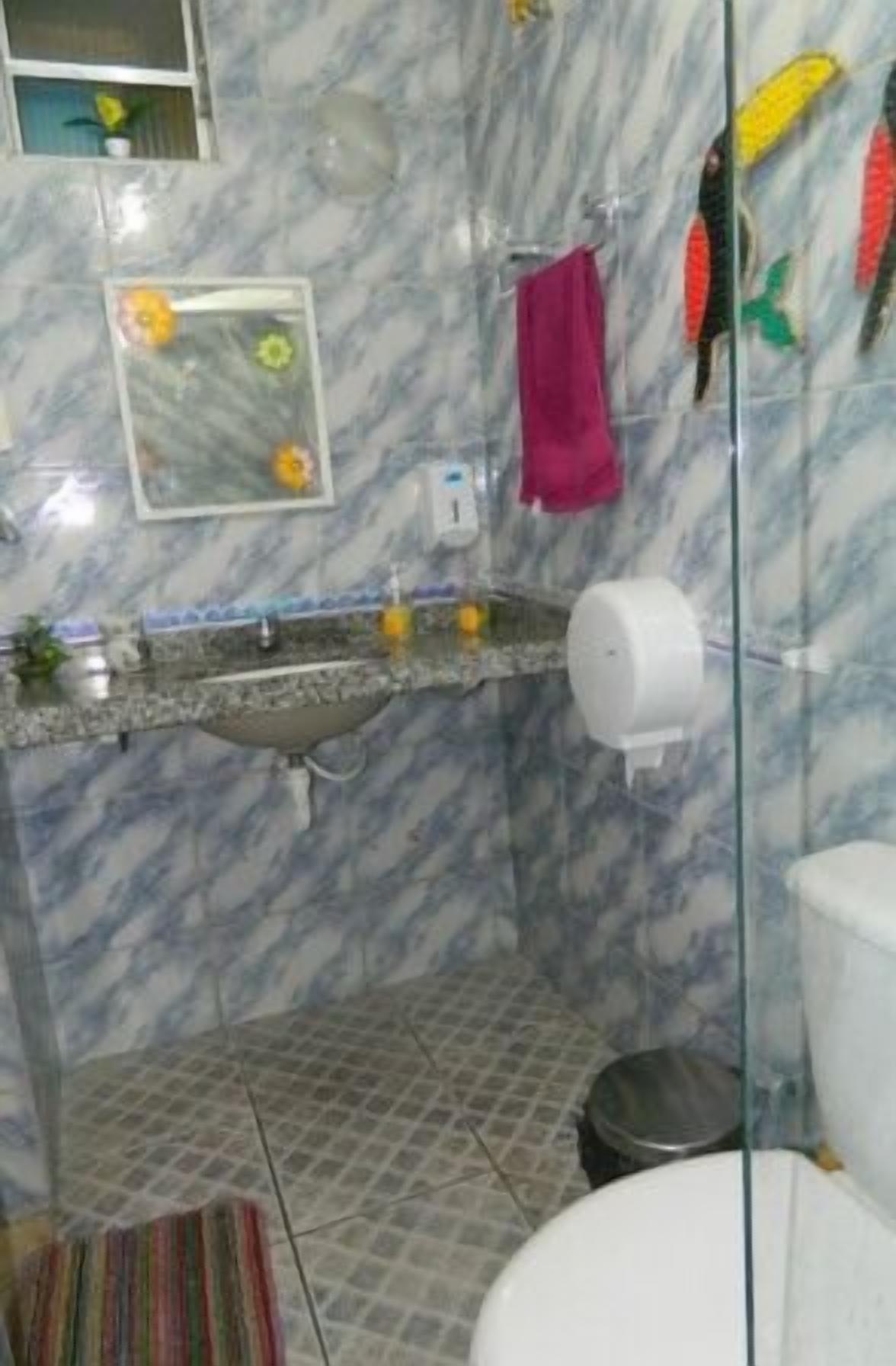 Un baño con salpicadero de mármol, un lavabo con espejo, inodoro y zona de ducha.