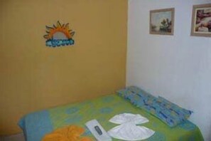 A small room with a bed, a wall clock, and a wall decoration of a sun and clouds. - Terra da Luz Hostel (Fortaleza)