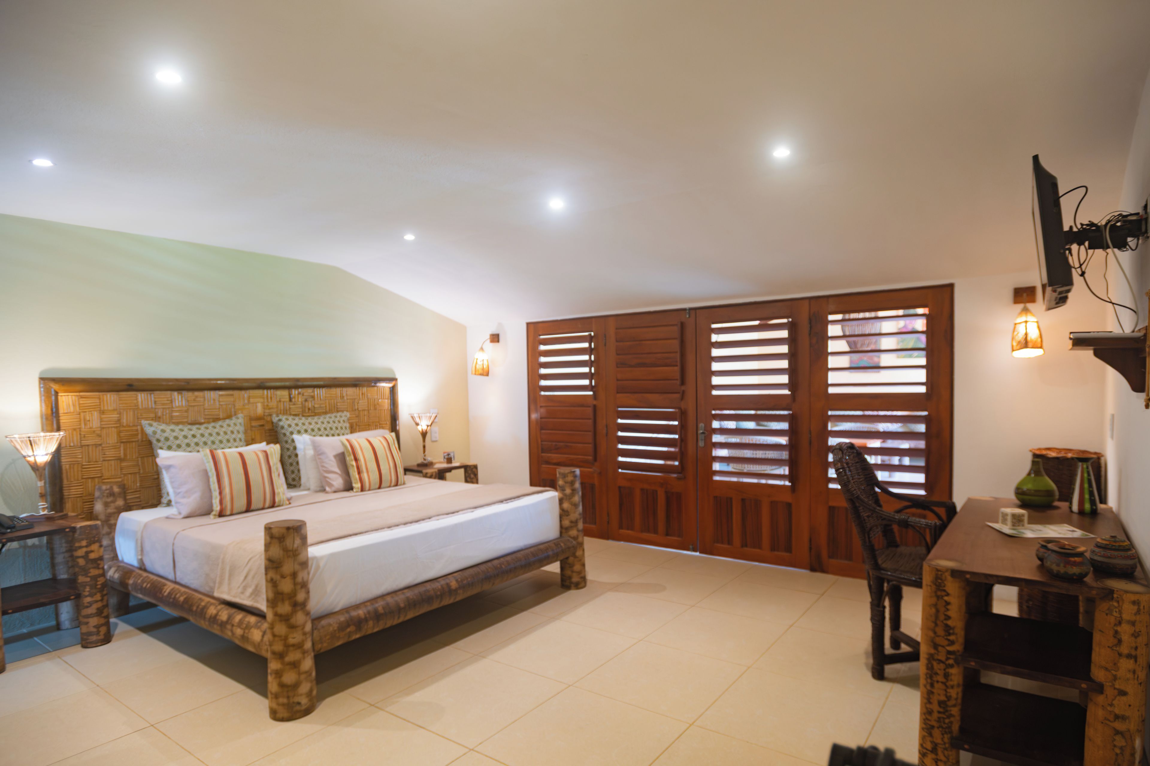 A bedroom with a bed, bedside tables, a desk, and a chair.
