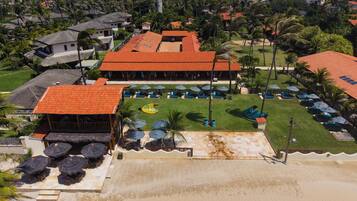 A resort with multiple buildings, a pool area with umbrellas, and a beach.