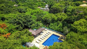 A pool area surrounded by lush greenery, with a clear view of the ocean and a cruise ship in the distance. - Hotel Miratlântico Búzios (Búzios)