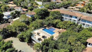 An aerial view of a residential area with a swimming pool surrounded by lush greenery and houses with tiled roofs. - Hotel Miratlântico Búzios (Búzios)