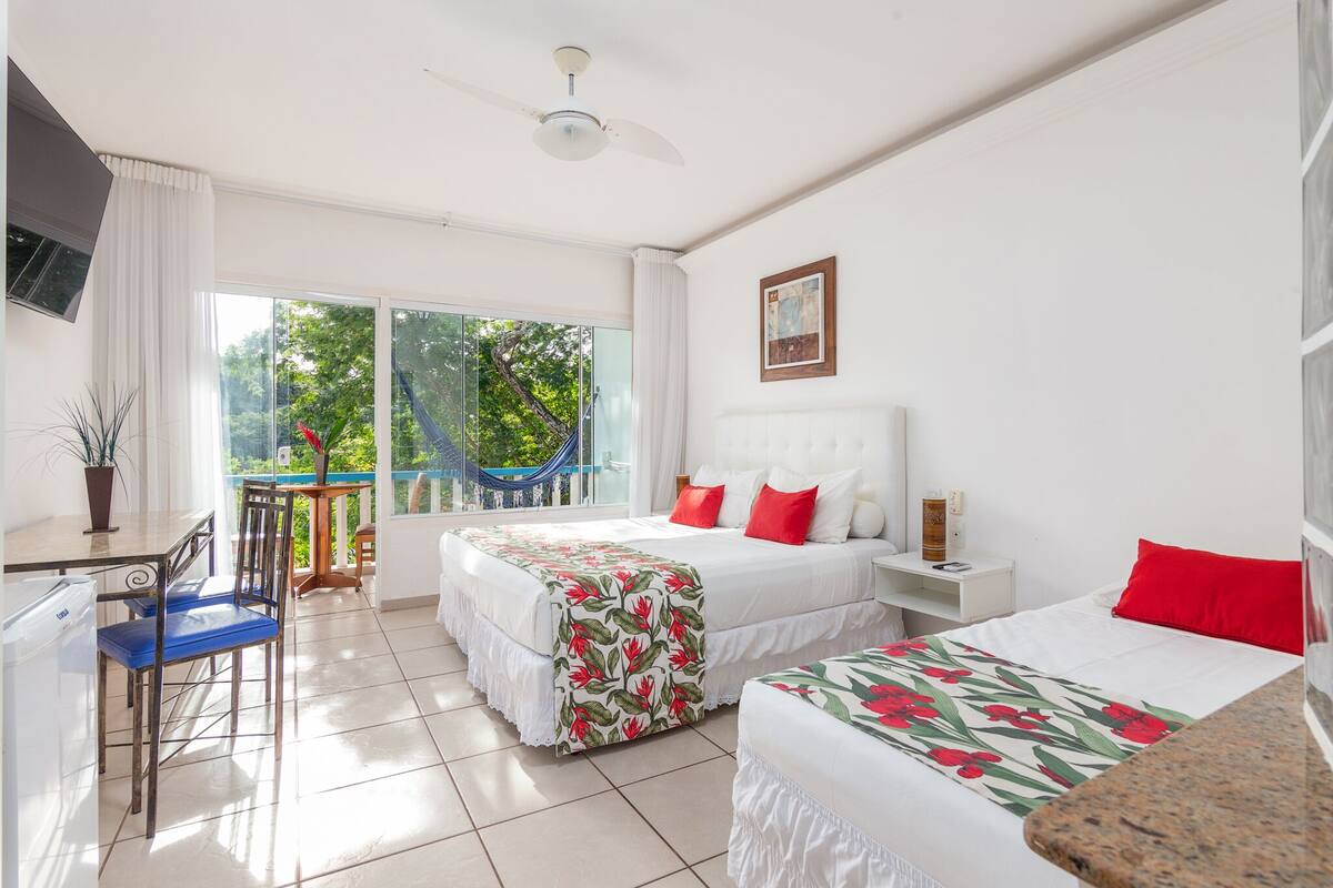 Une chambre d’hôtel avec deux lits, un bureau, une chaise et un balcon équipé d’un hamac.