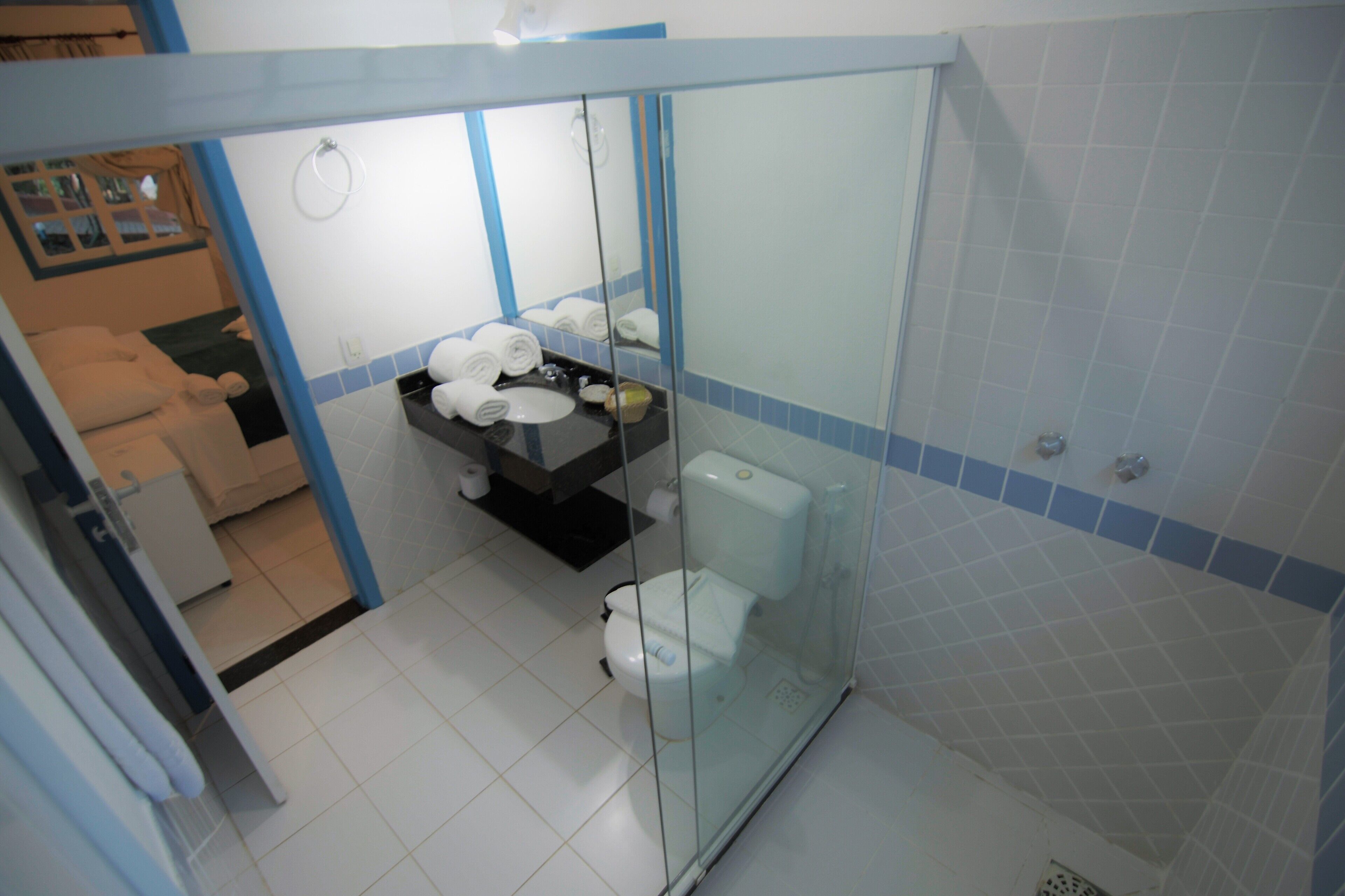 A bathroom with a glass shower enclosure, a toilet, and a sink with towels.