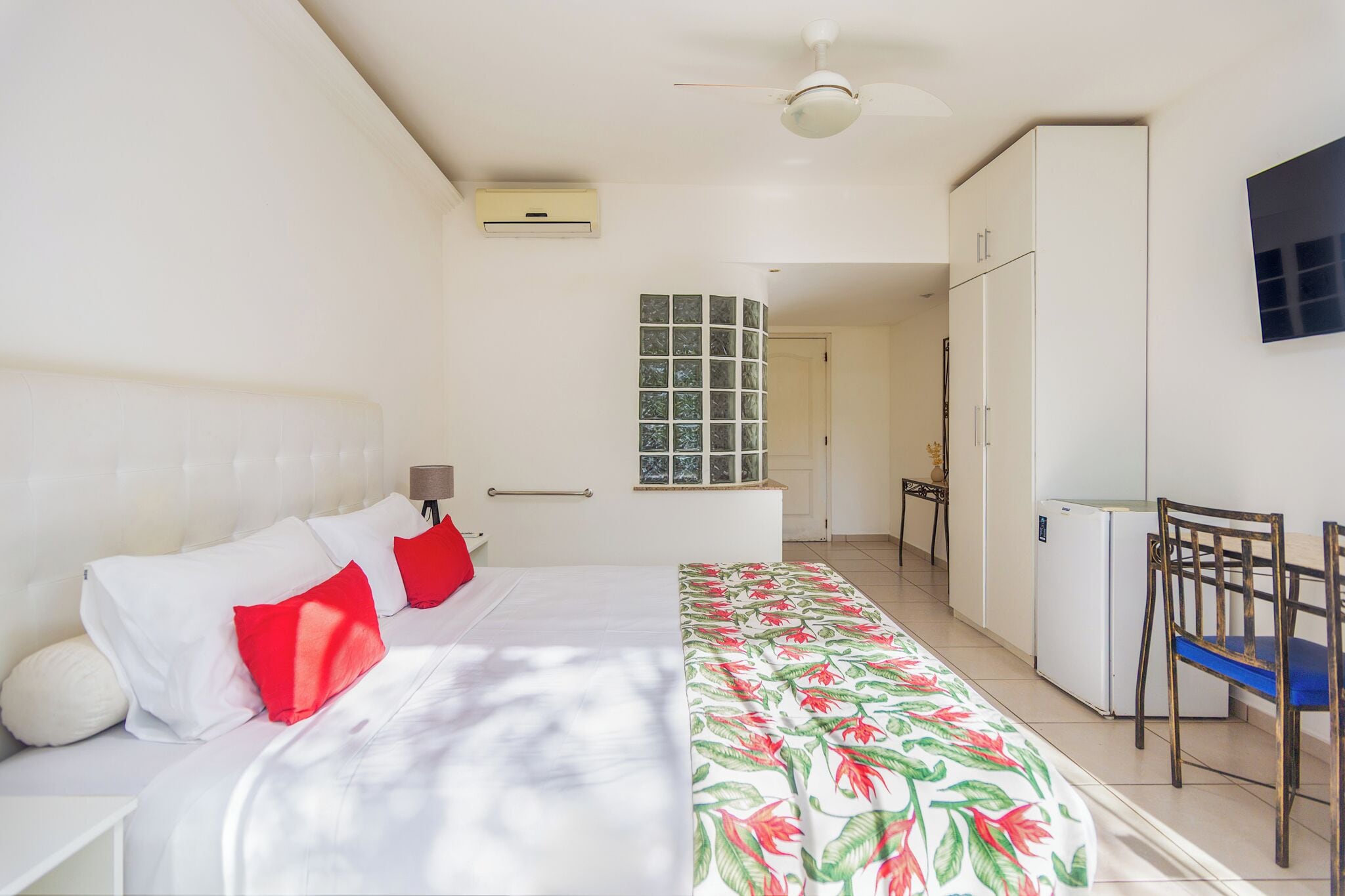 Een slaapkamer met een bed, een bureau, een stoel, een kledingkast en een televisie.