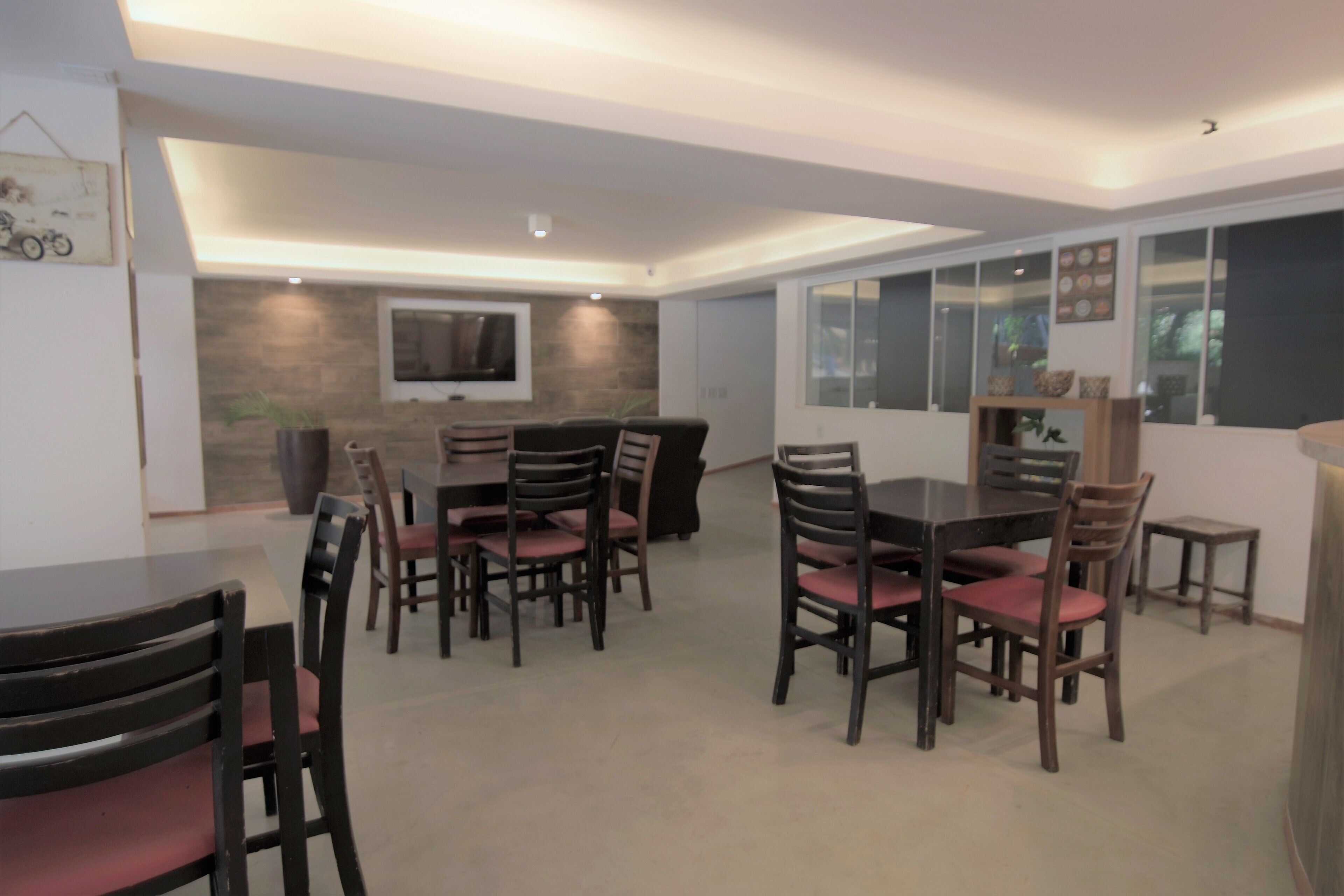 A dining area with a long table and chairs, a sofa, and a TV mounted on the wall.