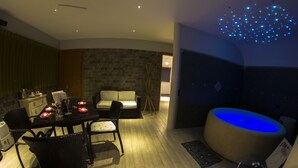 Un comedor moderno con una mesa dispuesta para dos, un arreglo de asientos y una pared de piedra.
