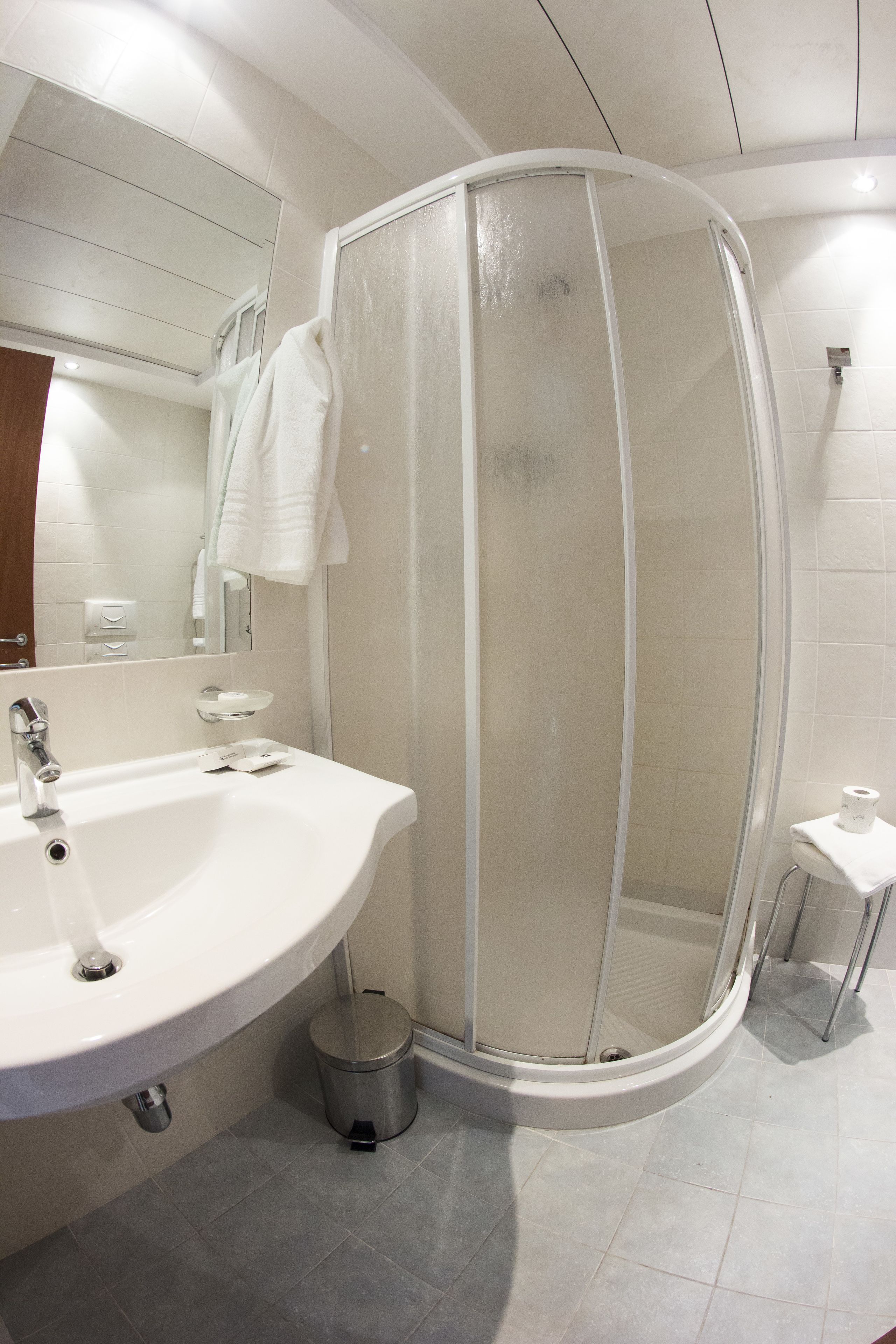 Une salle de bain moderne avec un lavabo blanc, un miroir et une cabine de douche.