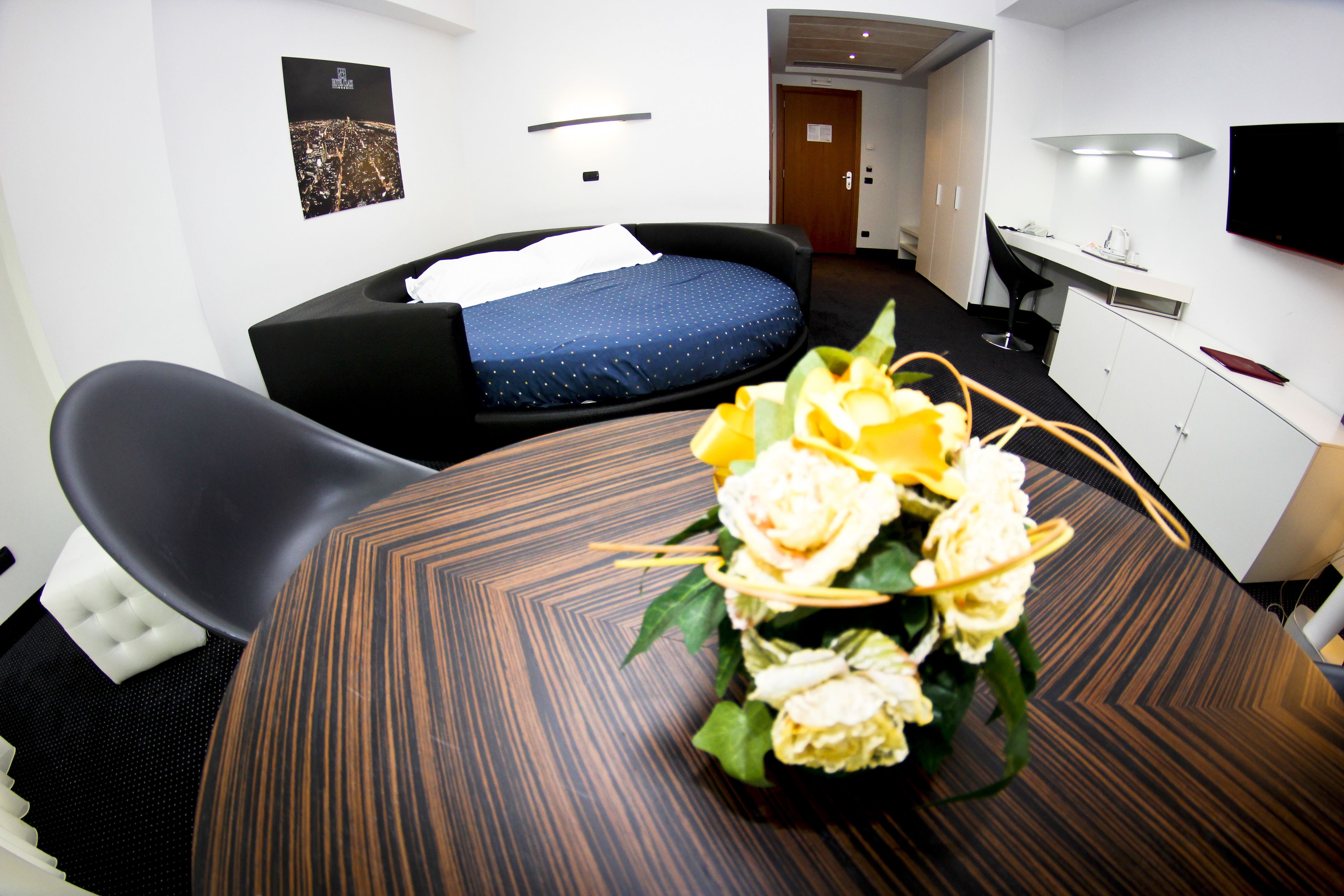 Una camera d'albergo con un letto, una scrivania, una sedia e un tavolo con un vaso di fiori.
