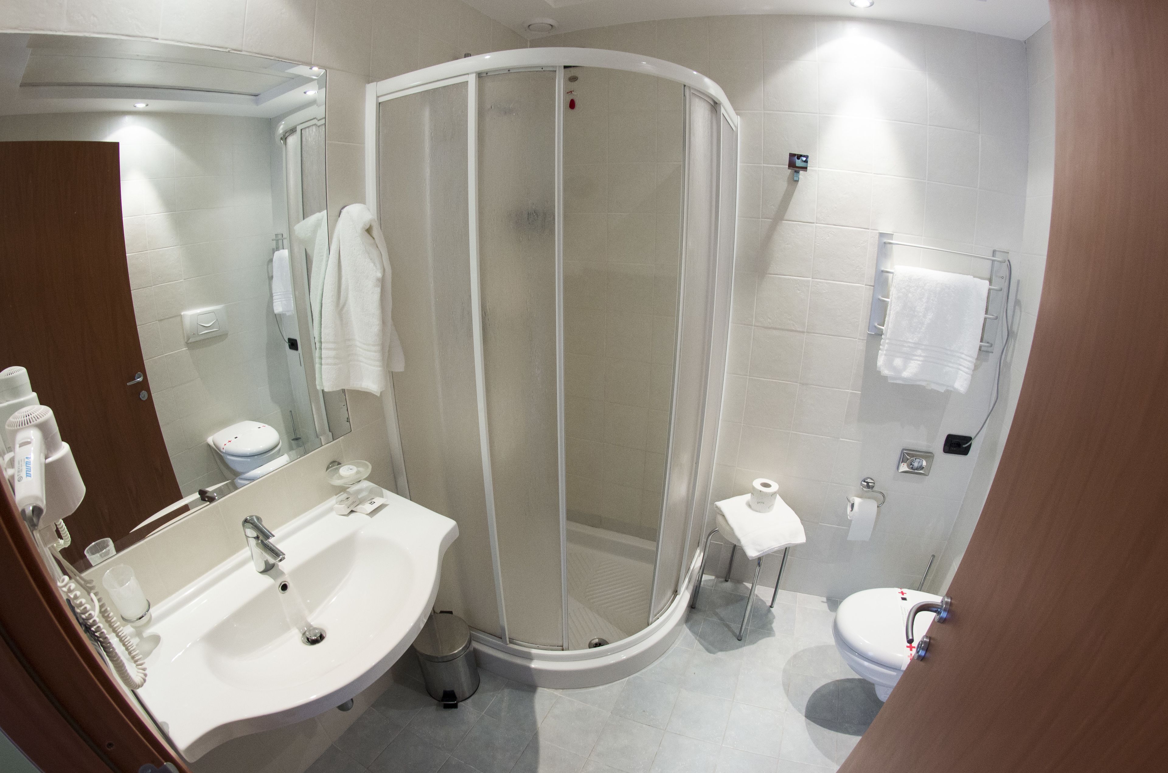 Un baño moderno con cabina de ducha curva, un lavabo con espejo y un inodoro.