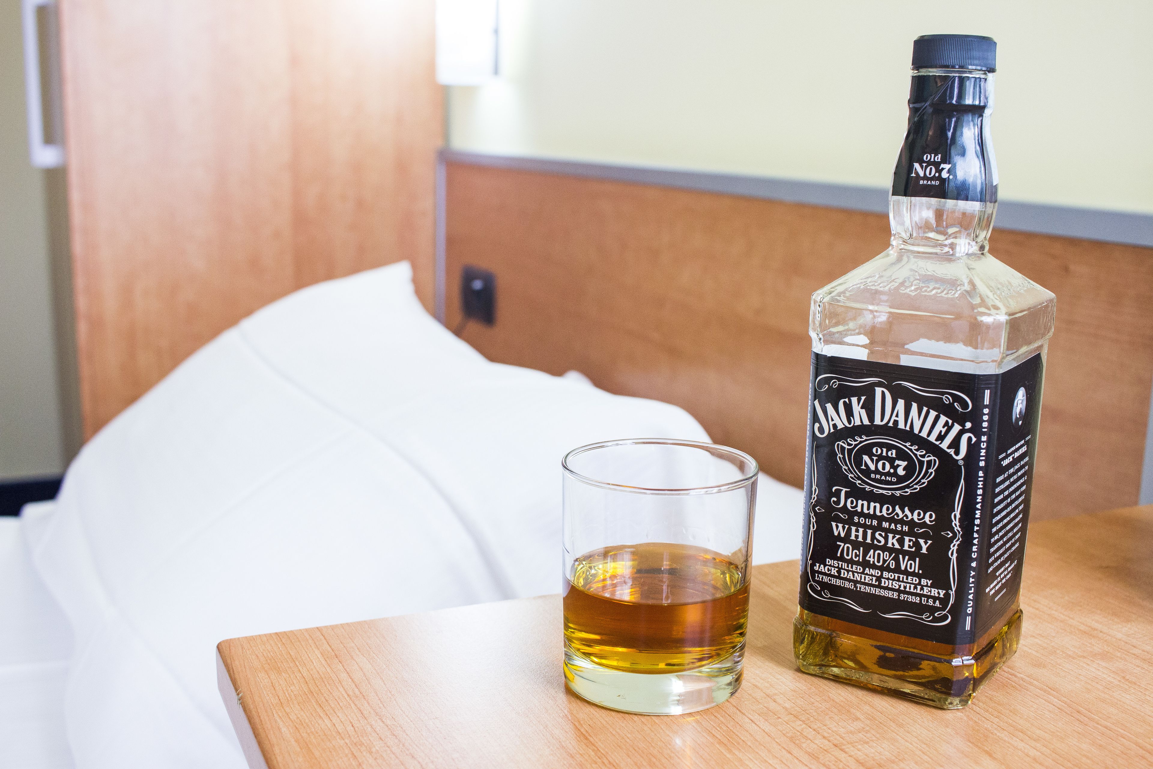 En flaske Jack Daniel's Tennessee Sour Mash Whiskey og et glas på et træbord i et hotelværelse.