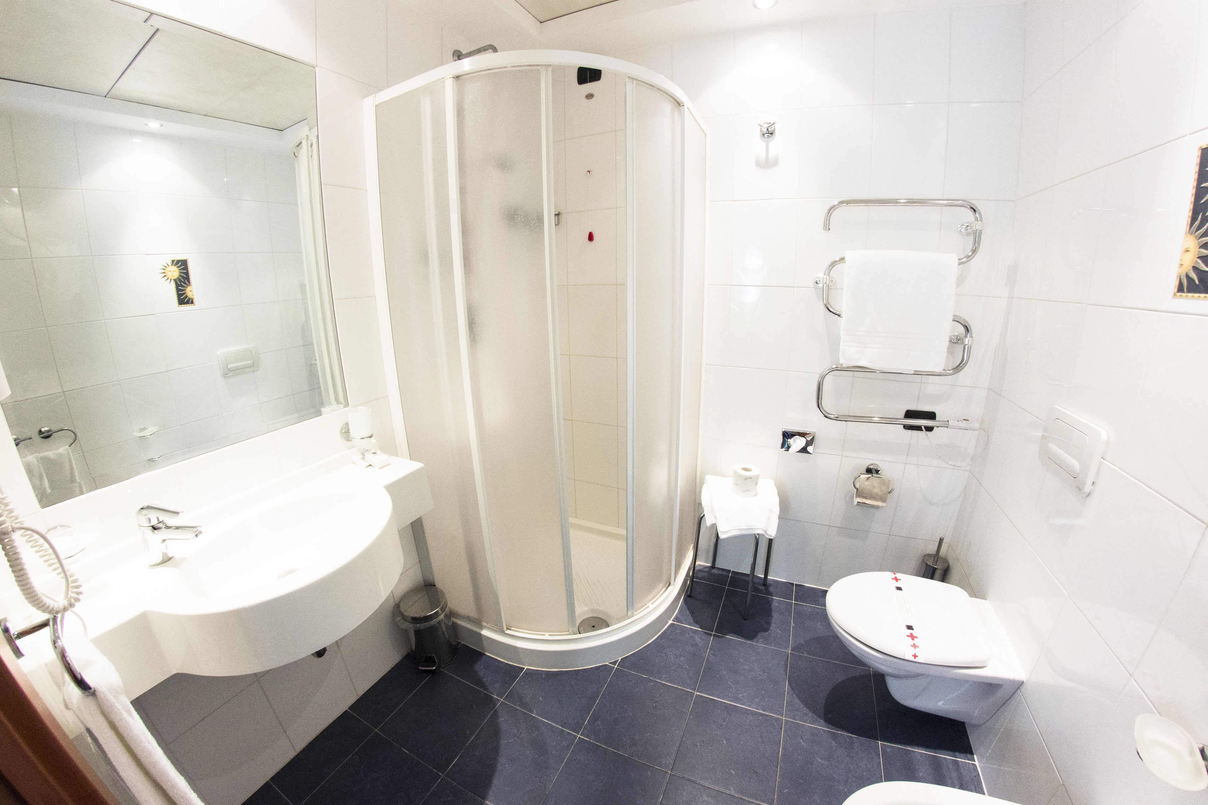 Un baño con ducha, inodoro, lavabo y perchero para toallas.