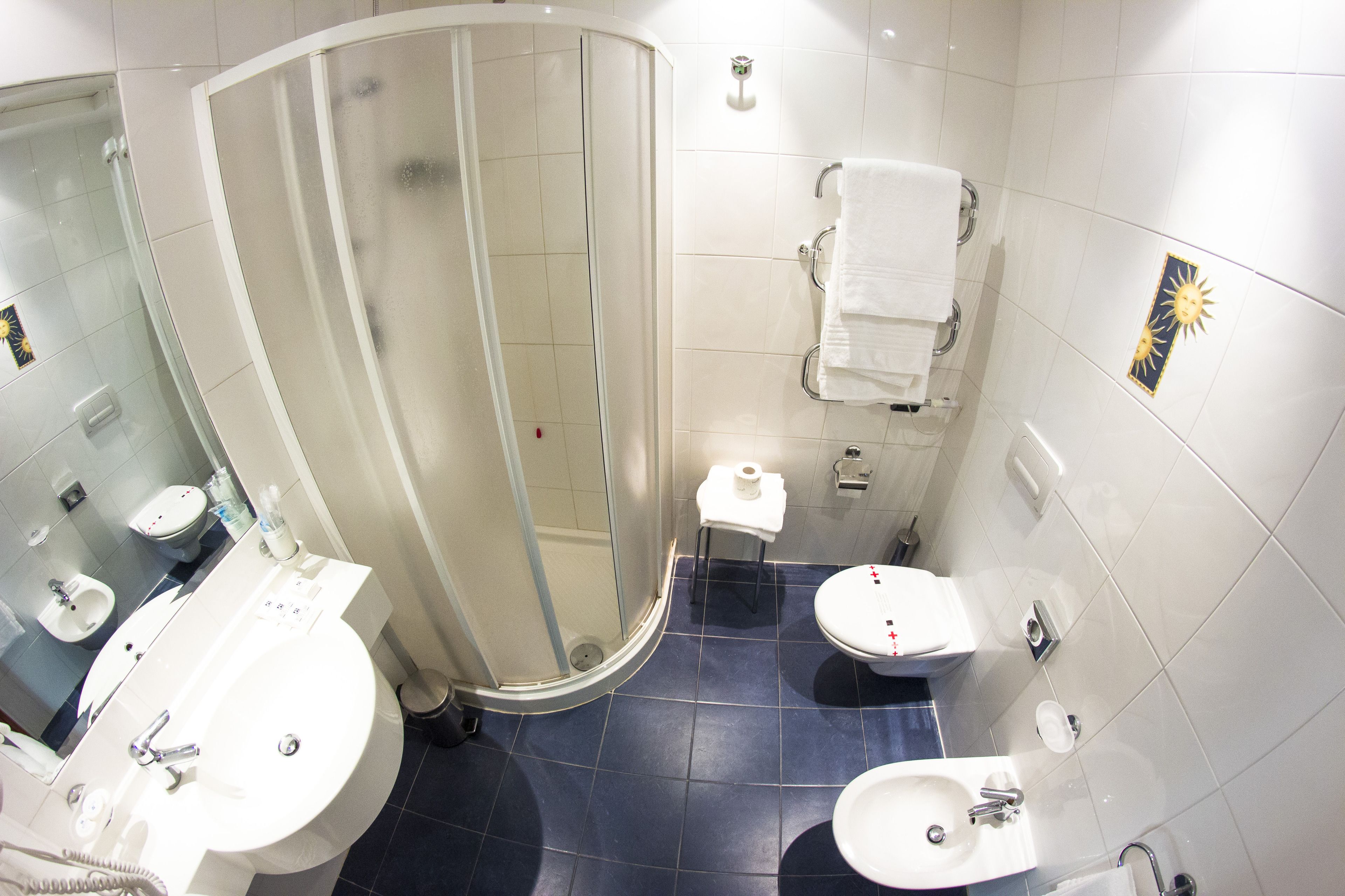 A modern bathroom with a glass-enclosed shower, a sink, a bidet, and a toilet.