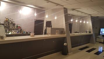Una zona de recepción moderna con mostrador, varias botellas, una máquina de café y un cubo de basura.