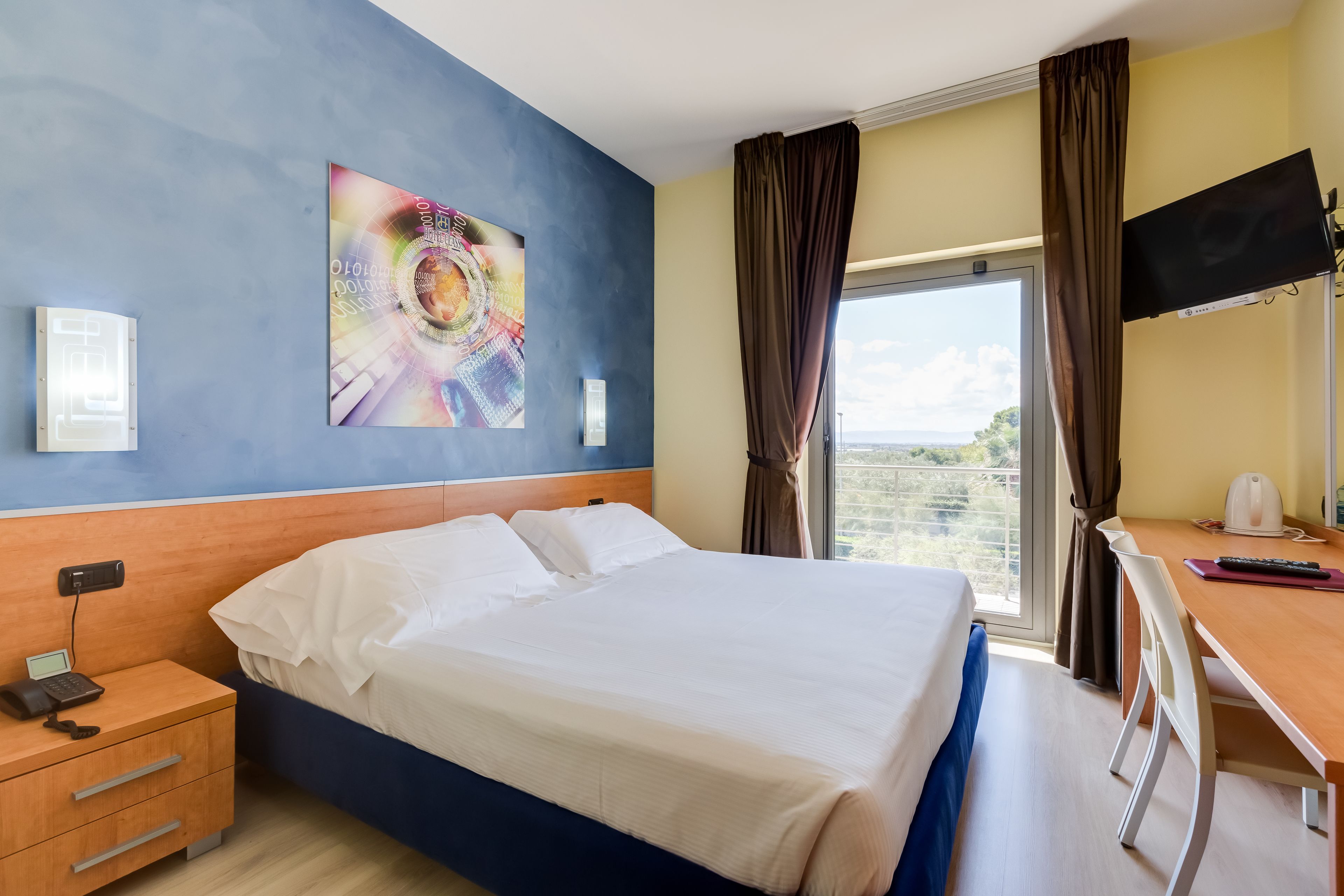 Une chambre d’hôtel avec un lit, un bureau et une grande fenêtre.