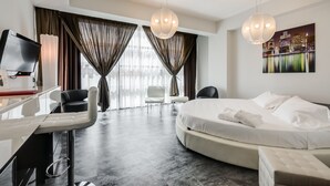 Una habitación de hotel moderna con una cama grande, un escritorio, una silla y un televisor.