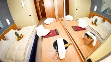 Une chambre d’hôtel avec deux lits, un minibar, un miroir et une porte donnant sur une autre chambre.