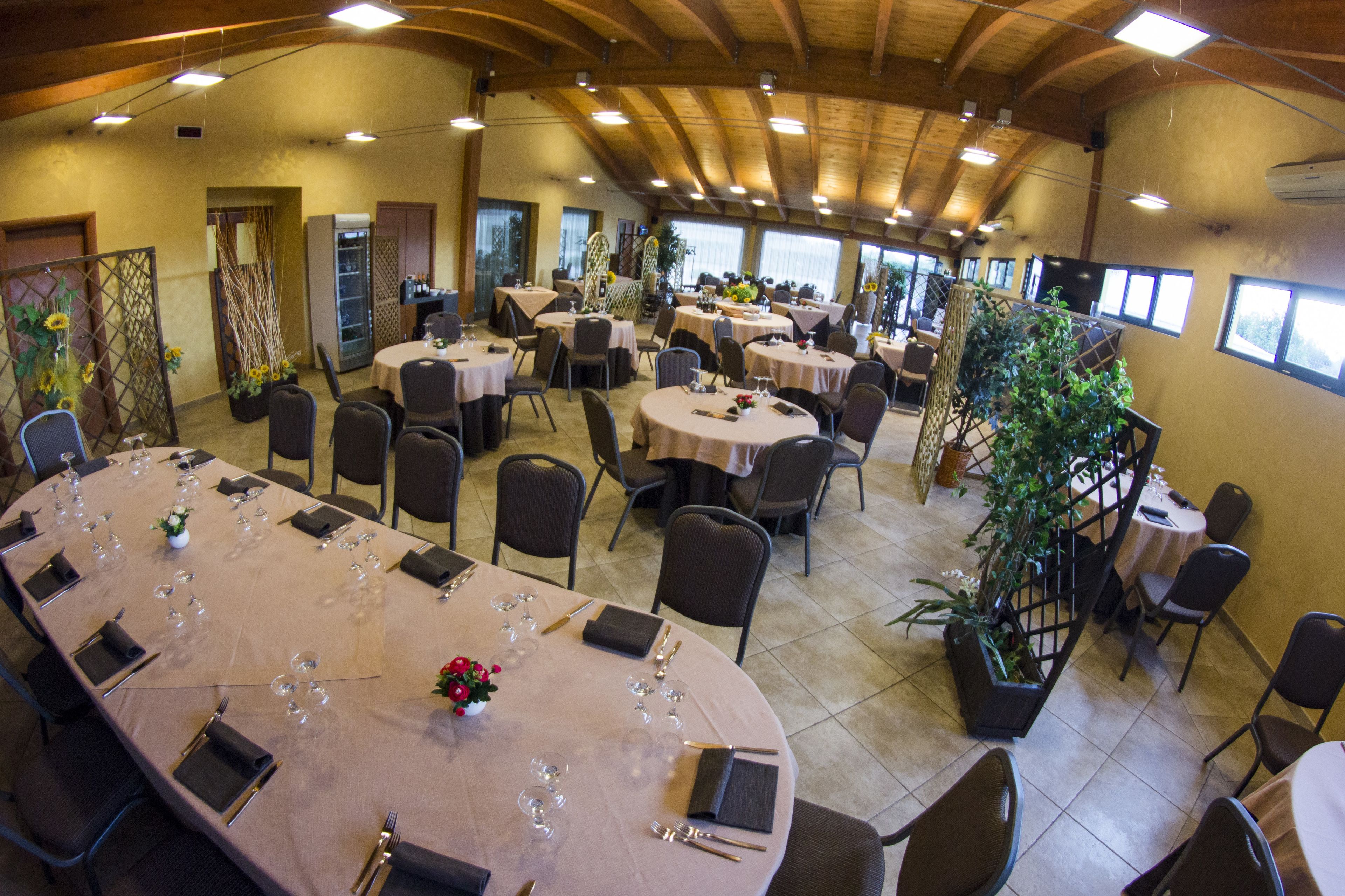 A spacious dining hall with multiple round tables set for dining, surrounded by chairs.