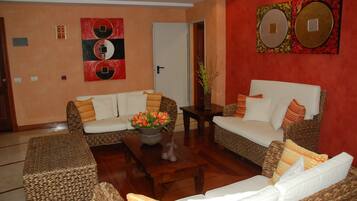 Una sala de estar con dos sofás blancos, una mesa de centro con flores y una pared de acento roja.