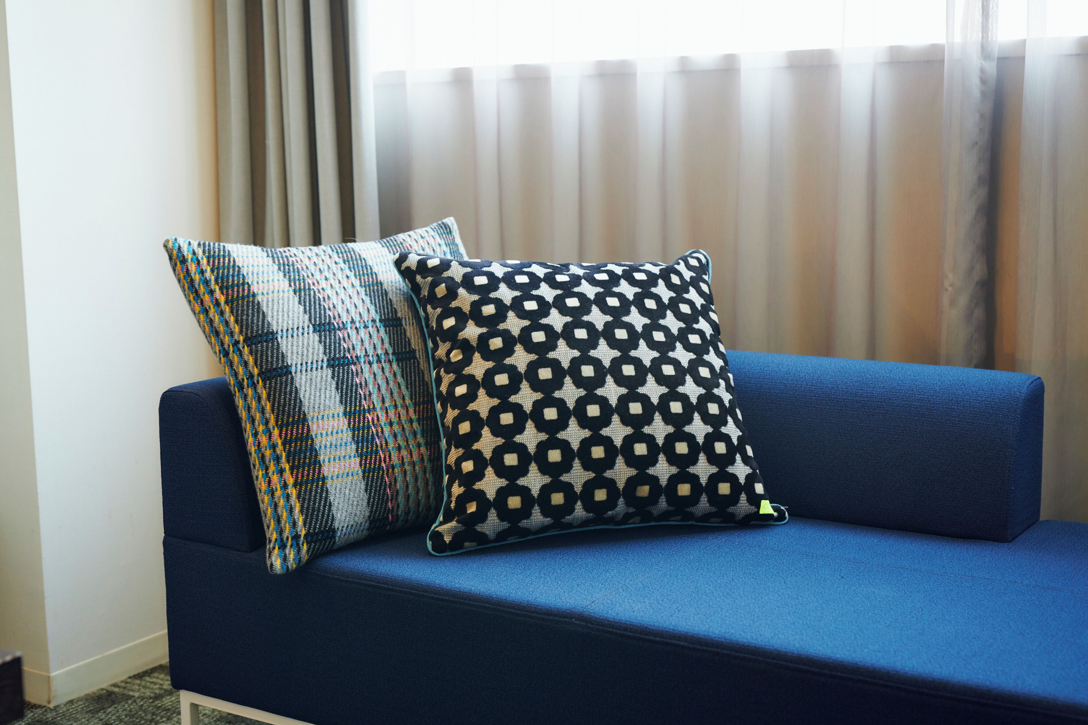 A blue sofa with two patterned pillows.