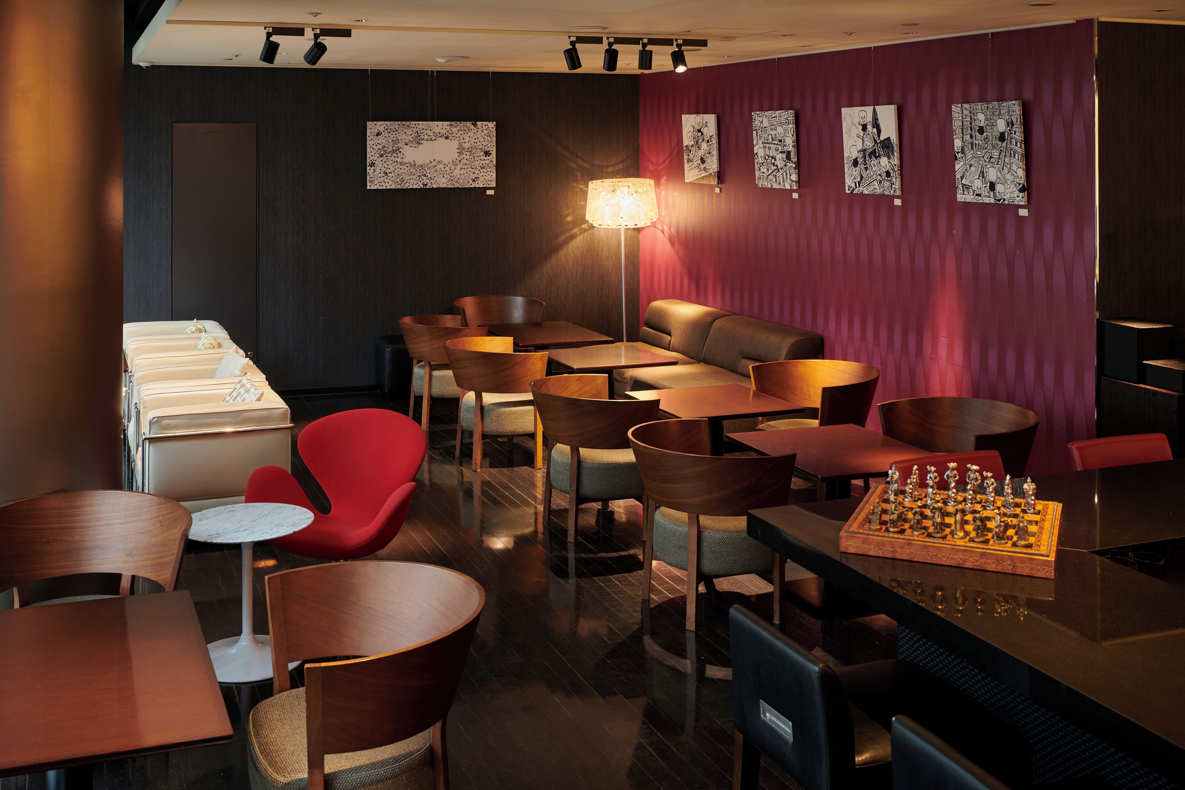 A modern lounge area with multiple seating options including tables, chairs, and a sofa. There is a chessboard on one of the tables.