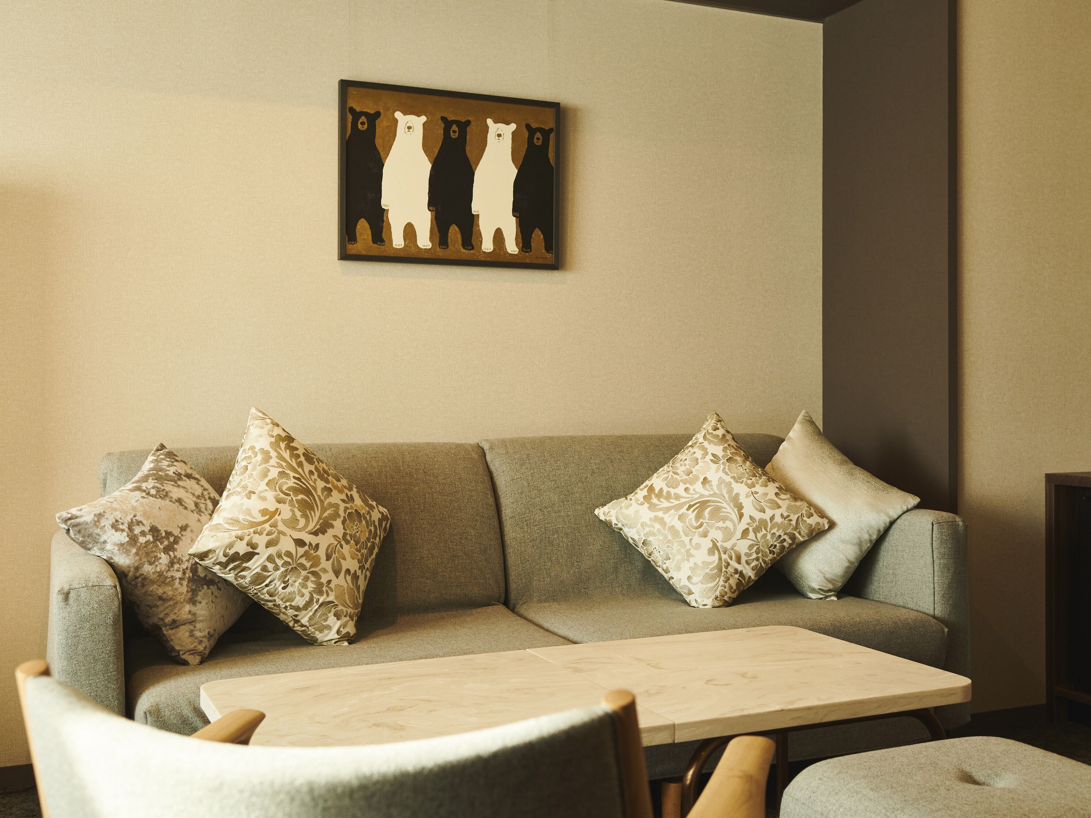 A living room with a sofa, two patterned pillows, a coffee table, and a wall-mounted artwork of bears.