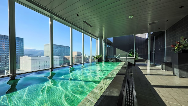 Piscina interior moderna con amplios ventanales que ofrecen vistas a la ciudad.