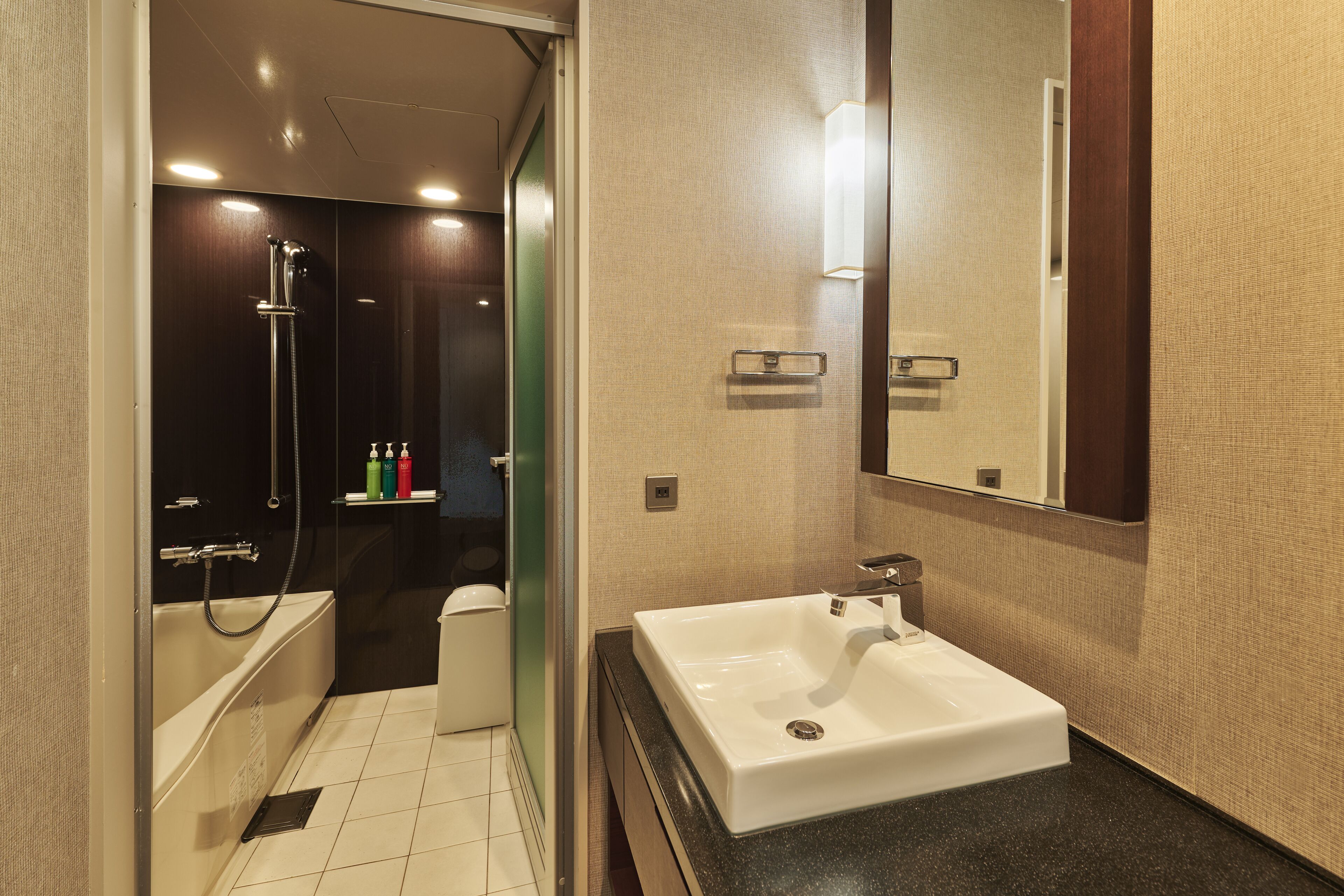 A modern bathroom with a white sink, a shower, and a toilet.