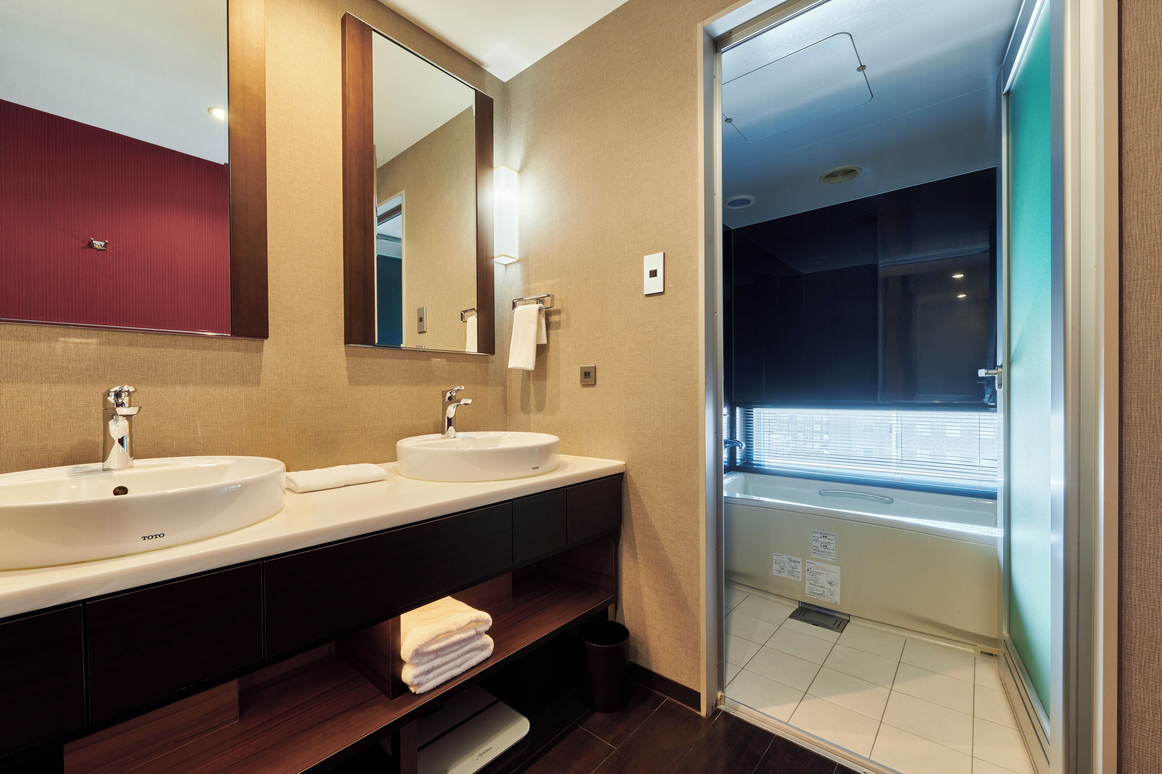 A modern bathroom with two sinks, a large mirror, and a glass shower enclosure.