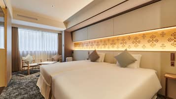 A hotel room with two beds, a desk, a chair, and a large window with curtains.