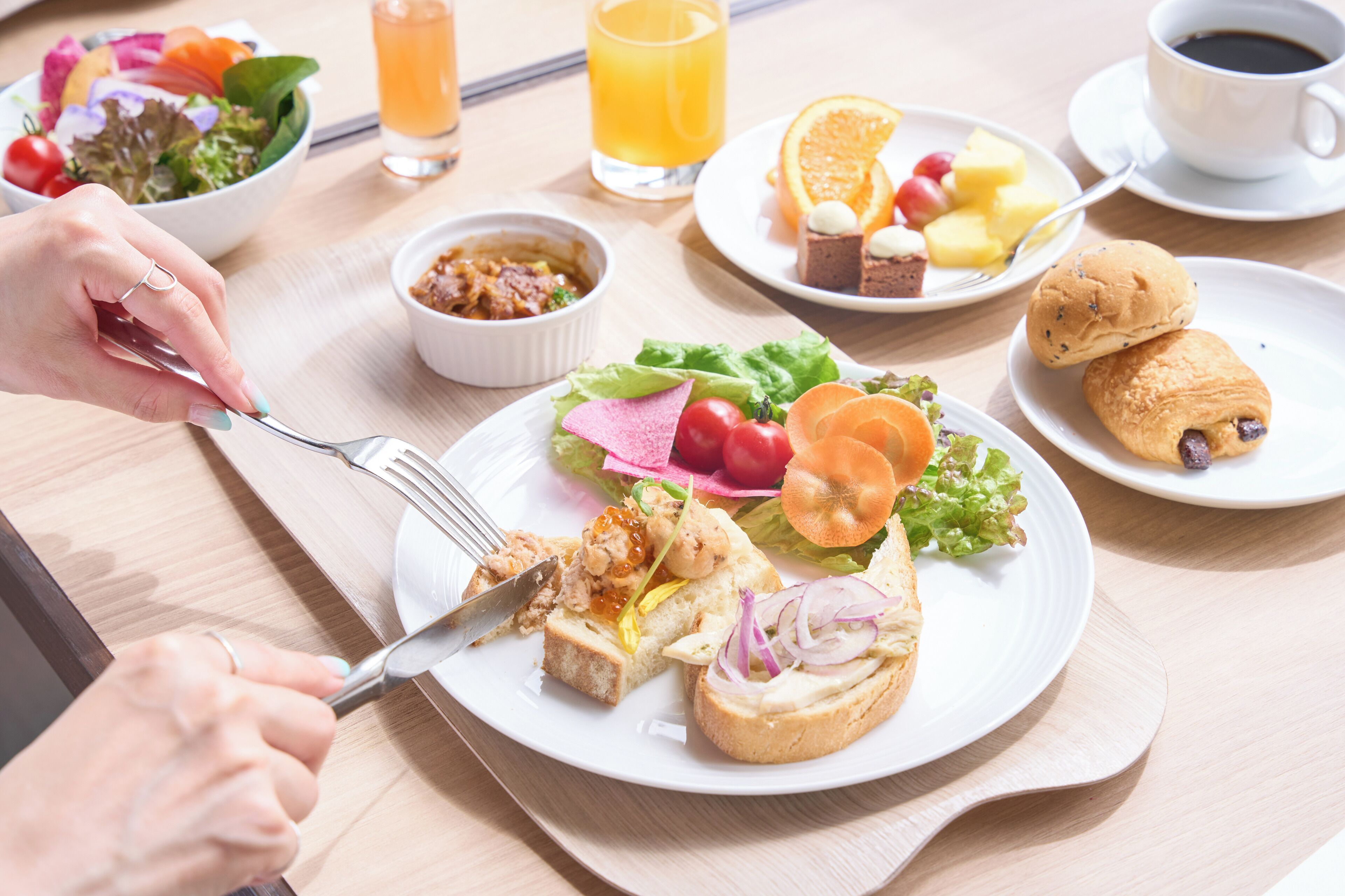 A breakfast setting with a variety of dishes including toast, salad, fruit, and pastries.