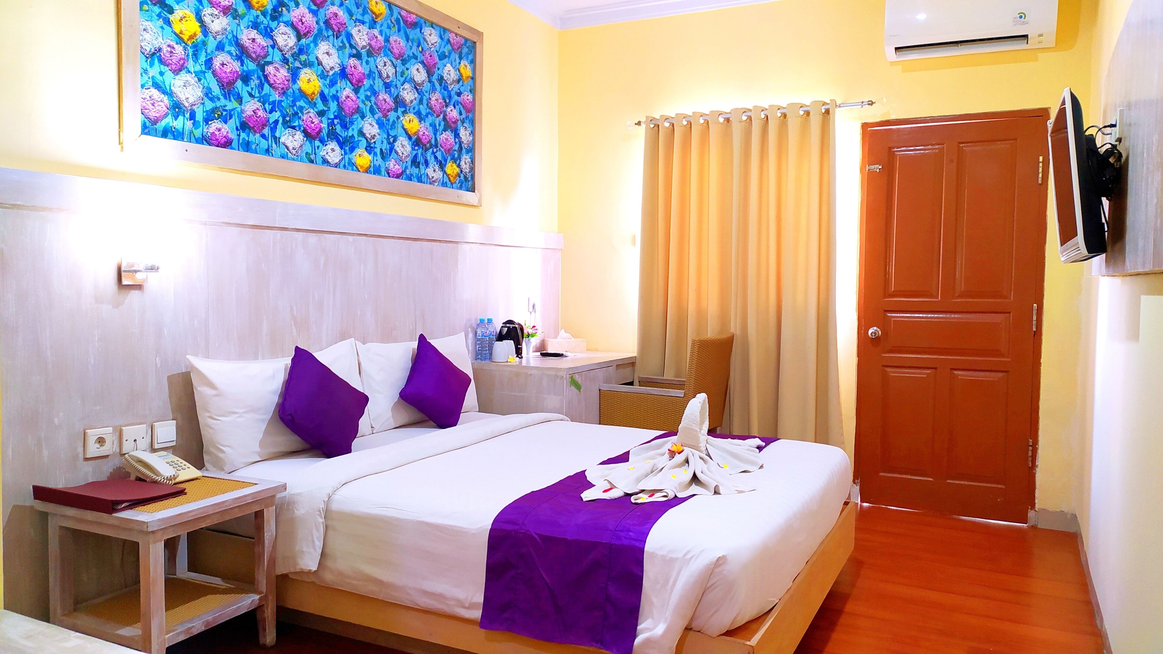 Une chambre d’hôtel avec un lit, une table de chevet, un bureau, une chaise, une porte et un tableau au mur.