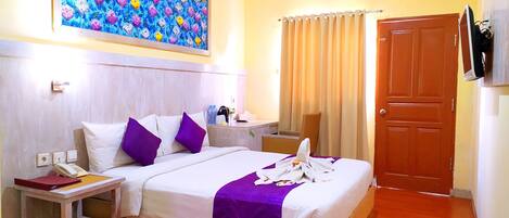 Une chambre d’hôtel avec un lit, une table de chevet, un bureau, une chaise, une porte et un tableau au mur.