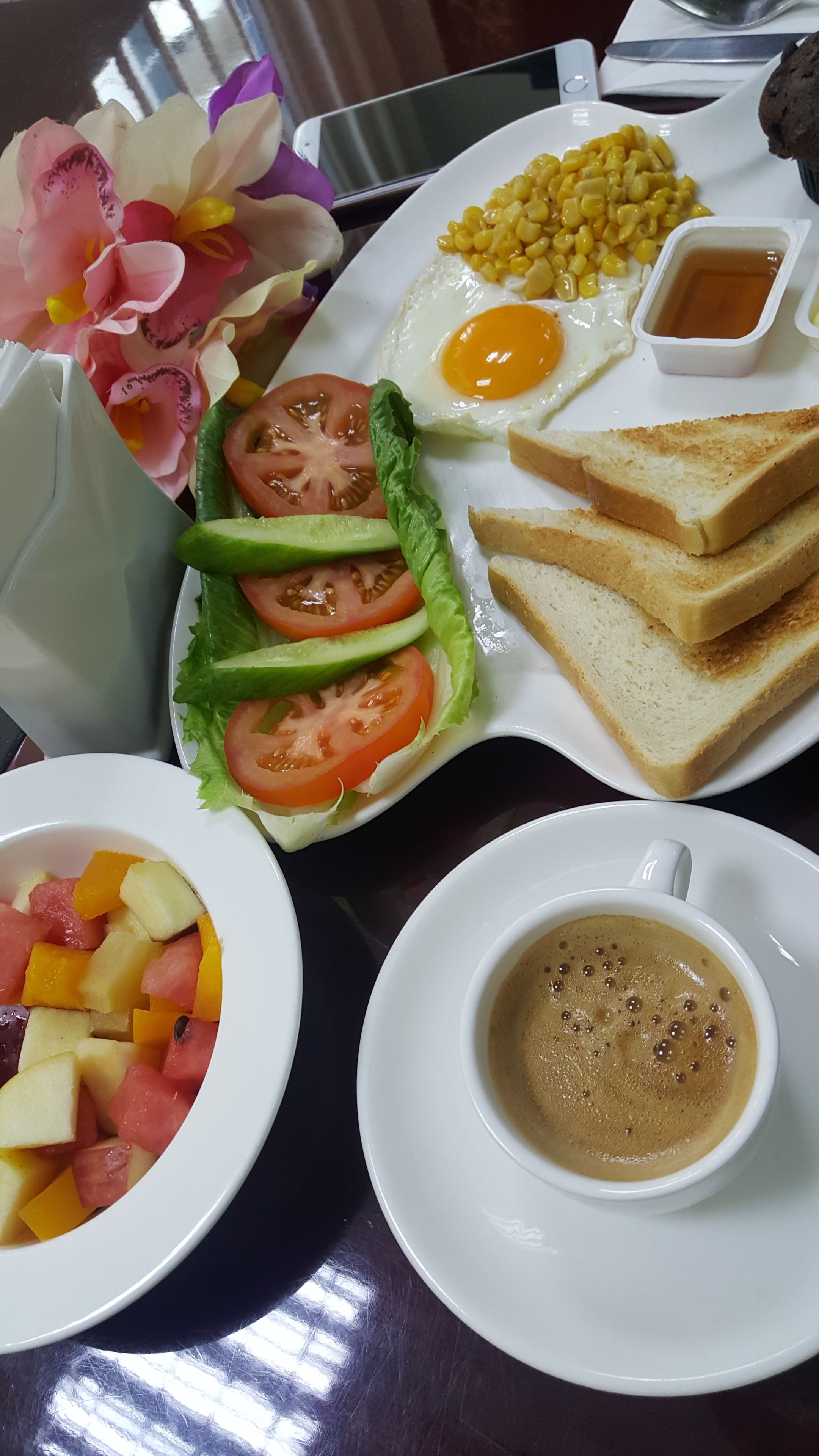 Een ontbijtbord met eieren, toast, mais en een salade.