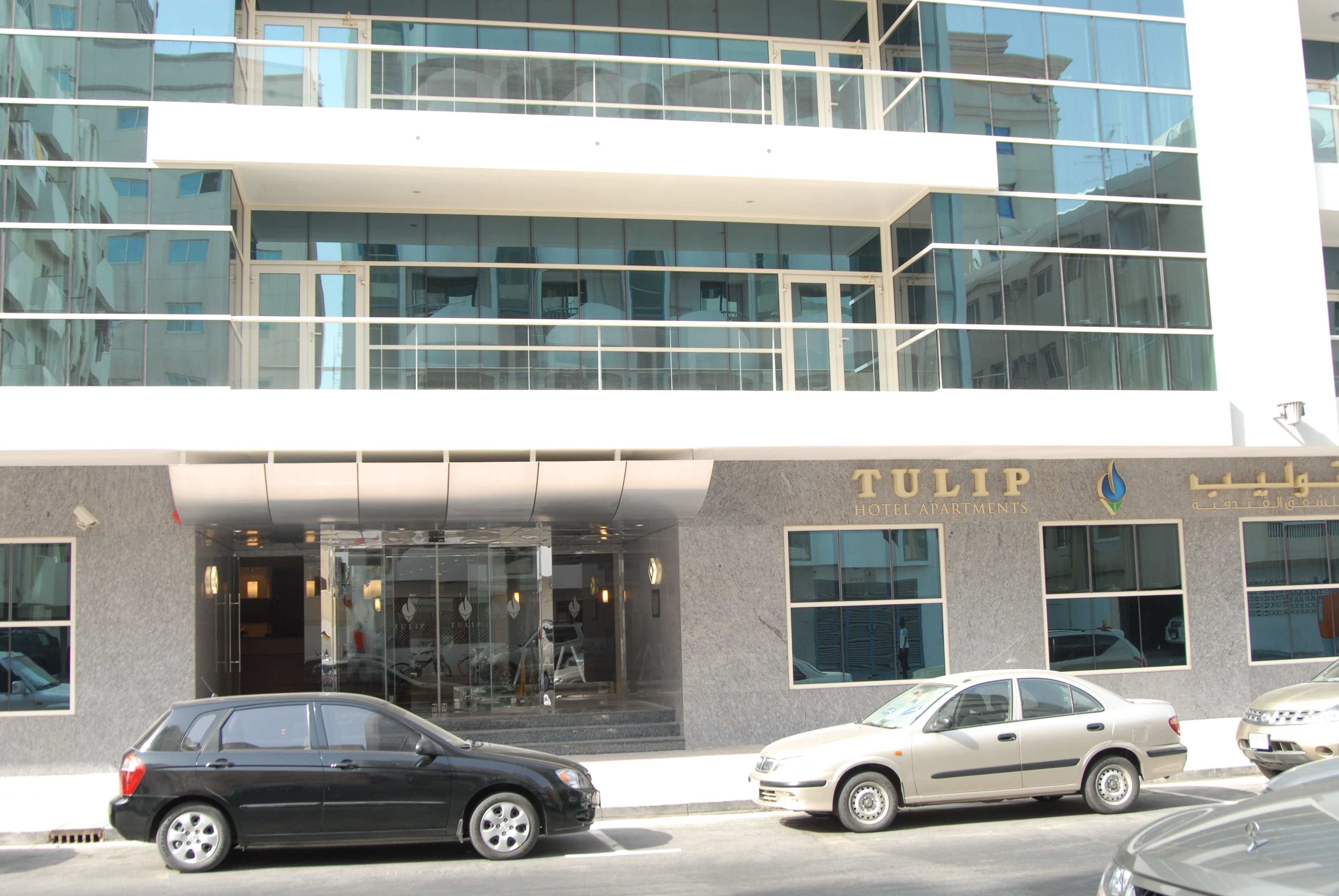 A modern building with a glass facade and a sign for 'TULIP HOTEL APARTMENTS'.