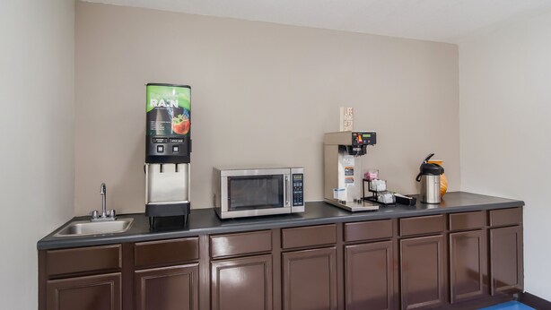 A kitchenette with a microwave, coffee machine, and a beverage dispenser.