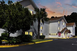A two-story motel with a red roof and a sign indicating a lobby.