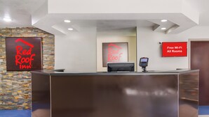A reception desk with a digital screen, a sign indicating free Wi-Fi, and a logo for Red Roof Inn. - Red Roof Inn Darien - I-95/ North Brunswick (Darien)