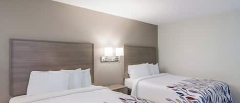 Een hotelkamer met twee bedden, elk voorzien van een hoofdeinde en een nachtkastje. Tussen de bedden hangen twee wandlampen.