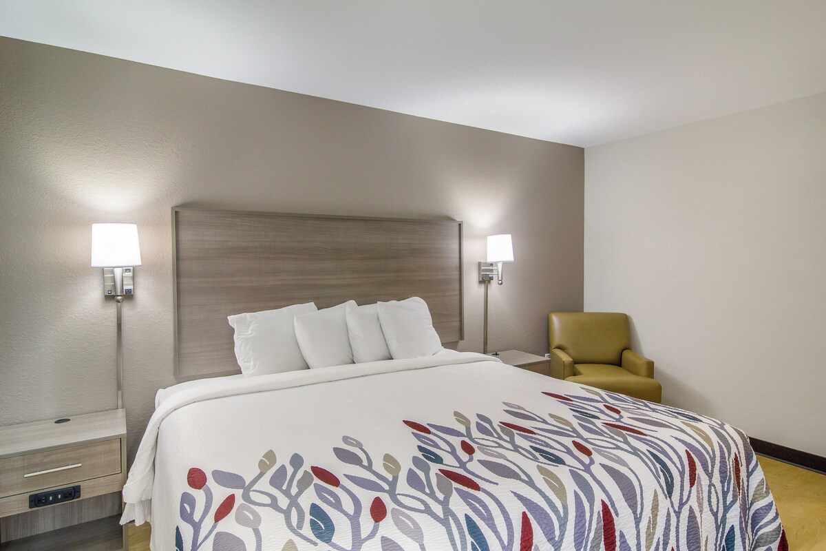 A hotel room with a bed, two bedside lamps, a chair, and a nightstand.